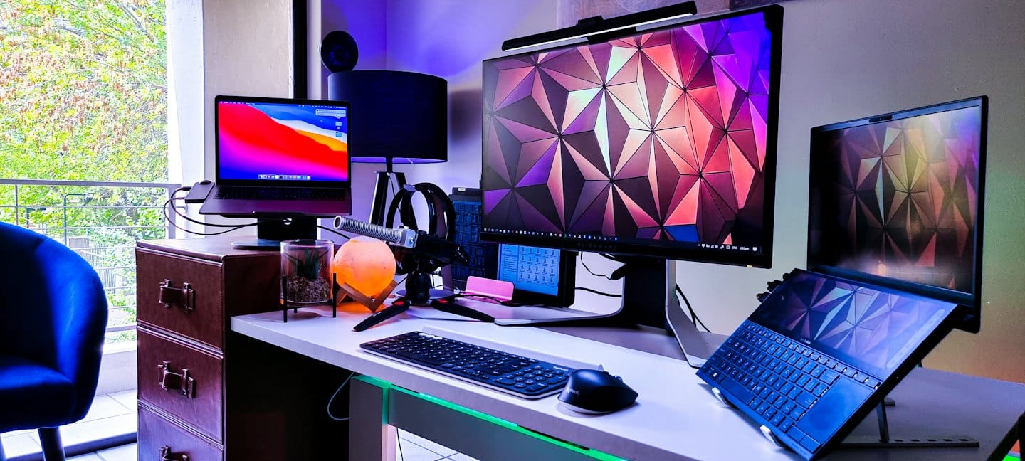 Moderno ufficio domestico con più schermi di computer e illuminazione RGB.